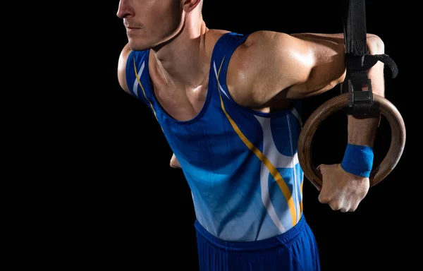 Treinamento de ginasta masculino muscular em ginásio, flexível e ativo. Caucasiano em forma cara, atleta de sportswear azul isolado em preto — Fotografia de Stock