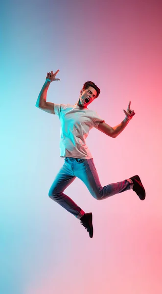 Joven caucásico mans retrato en gradiente azul-rosa estudio fondo en luz de neón — Foto de Stock