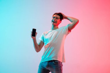 Neon ışıklarıyla mavi-pembe stüdyo arka planında beyaz adam portresi