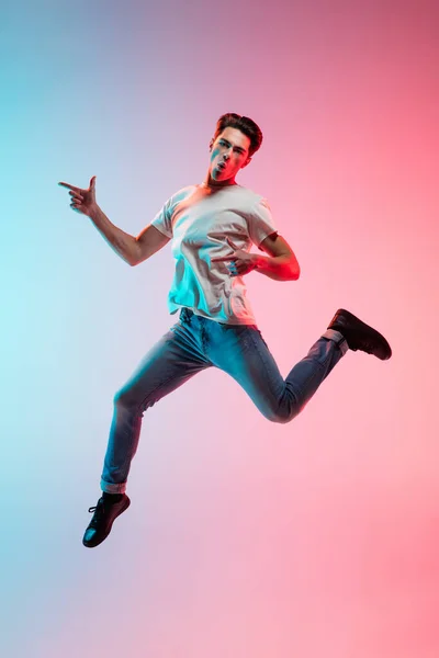 Young caucasian mans portrait on gradient blue-pink studio background in neon light — Stock Photo, Image