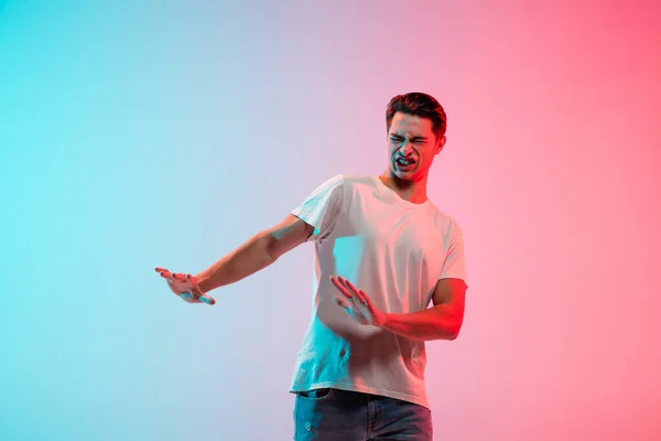 Young caucasian mans portrait on gradient blue-pink studio background in neon light — Stock Photo, Image