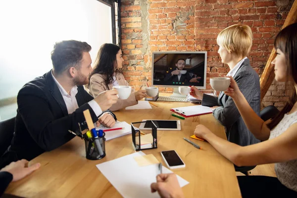 Les jeunes parlent, travaillent pendant la vidéoconférence avec des collègues au bureau ou dans le salon — Photo