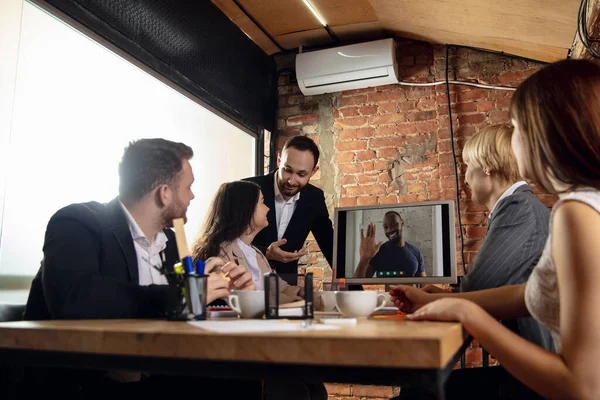 Young people talking, working during videoconference with colleagues at office or living room