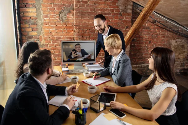 Young people talking, working during videoconference with colleagues at office or living room