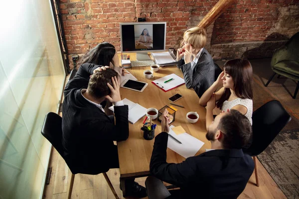 Les jeunes parlent, travaillent pendant la vidéoconférence avec des collègues au bureau ou dans le salon — Photo