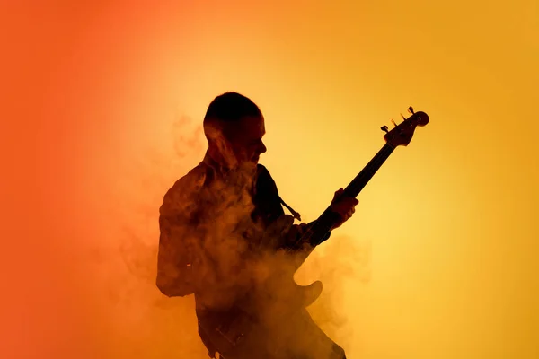 네온 빛을 받은 스튜디오 배경에 고립되어 있는 젊은 코카서스 남자 기타 연주자 의 실루엣 — 스톡 사진