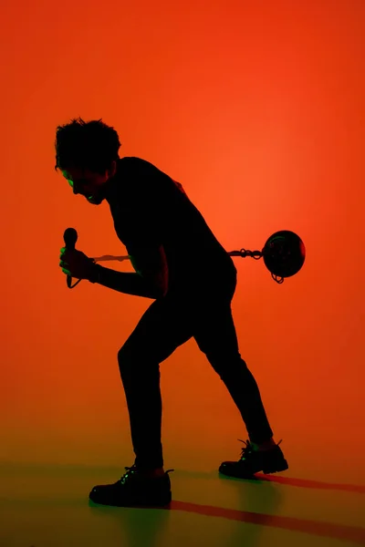 Silhouette eines jungen kaukasischen männlichen Sängers isoliert auf orangefarbenem Studiohintergrund im Neonlicht — Stockfoto