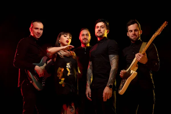 Musikerband isoliert auf dunklem Studiohintergrund in Neonlicht — Stockfoto
