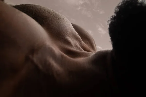 Textura detallada de la piel humana. Primer plano de cuerpo masculino afroamericano joven como paisaje con el fondo del cielo —  Fotos de Stock