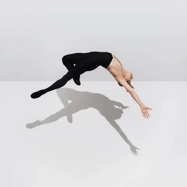 Bella giovane atleta di sesso maschile che pratica su sfondo bianco studio con ombre in salto, aria di volo — Foto Stock