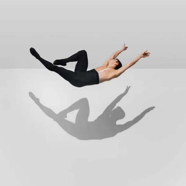 Beau jeune athlète masculin pratiquant sur fond de studio blanc avec des ombres en saut, vol à l'air — Photo