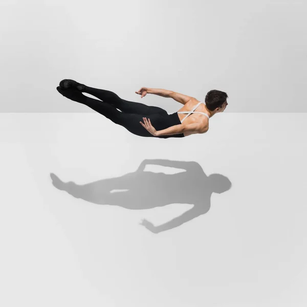 Krásný mladý samec sportovec cvičit na bílém pozadí studia se stíny ve skoku, vzduch létání — Stock fotografie
