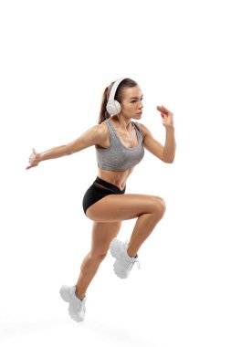 Beyaz stüdyo arka planında izole edilmiş beyaz kadın koşucu, atlet eğitimi. Reklam için kopyalama alanı.