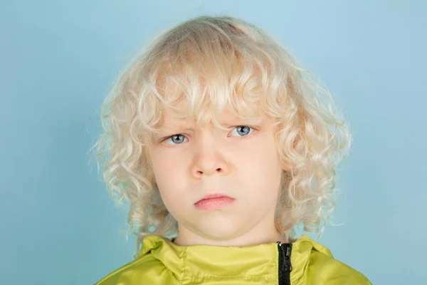 Portrett av en vakker, kaukasisk liten gutt isolert på blå studiobakgrunn – stockfoto