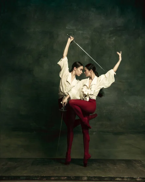 Twee jonge vrouwelijke balletdansers houden van duellisten met zwaarden. Ballet en hedendaagse choreografie concept. Creatieve kunst foto. — Stockfoto