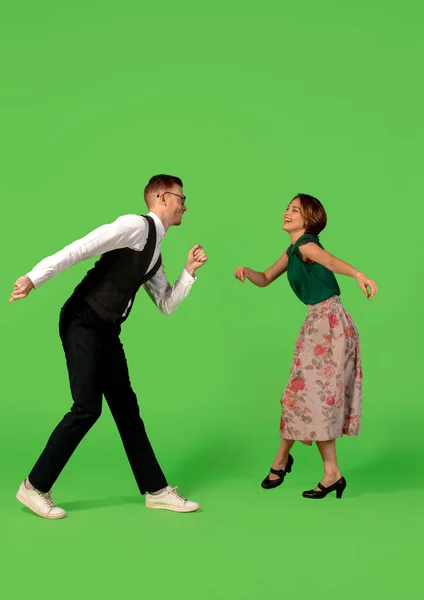 Old-school fashioned young woman dancing isolated on green background