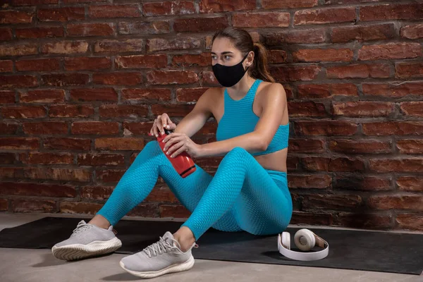 Treinamento atleta profissional feminino no fundo da parede de tijolo usando máscara facial. Desporto durante a quarentena — Fotografia de Stock