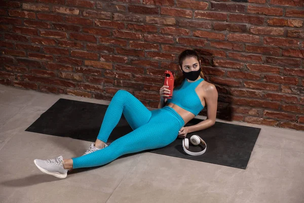 Treinamento atleta profissional feminino no fundo da parede de tijolo usando máscara facial. Desporto durante a quarentena — Fotografia de Stock