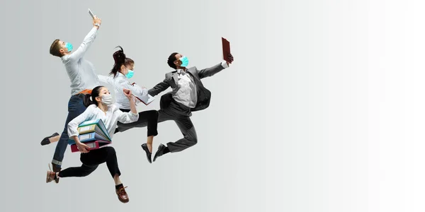 Happy office workers in face masks jumping and dancing in casual clothes or suit isolated on studio background. Creative collage. — Stock Photo, Image