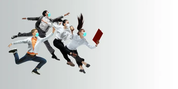 Happy office workers in face masks jumping and dancing in casual clothes or suit isolated on studio background. Creative collage. — Stock Photo, Image