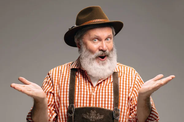 Happy senior man dressed in traditional Austrian or Bavarian costume gesturing isolated on grey studio background — Stock Fotó