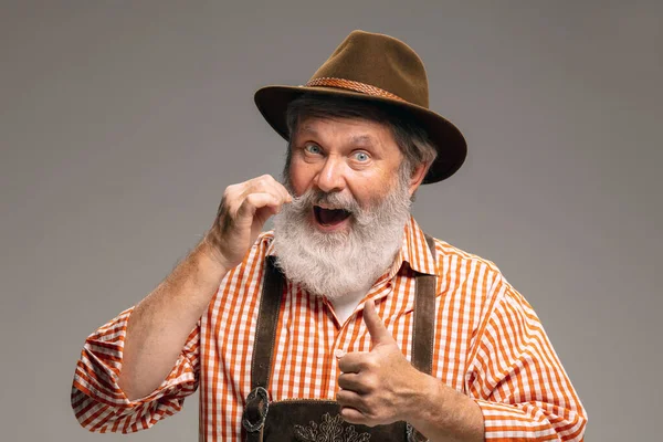 Happy senior man dressed in traditional Austrian or Bavarian costume gesturing isolated on grey studio background — Stock Fotó