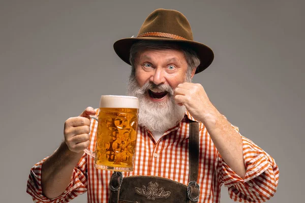 Happy senior man dressed in traditional Austrian or Bavarian costume gesturing isolated on grey studio background — Stock Photo, Image