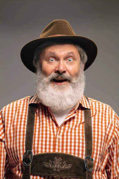 Happy senior man dressed in traditional Austrian or Bavarian costume gesturing isolated on grey studio background — Stock Fotó