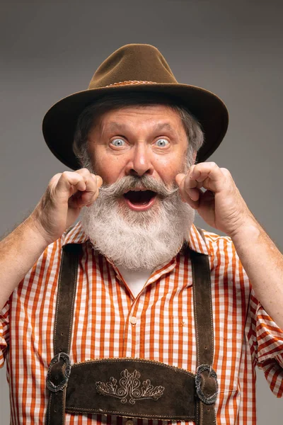 Ευτυχισμένος ηλικιωμένος άνδρας ντυμένος με την παραδοσιακή αυστριακή ή βαυαρική στολή gesturing απομονωμένος σε γκρι φόντο στούντιο — Φωτογραφία Αρχείου
