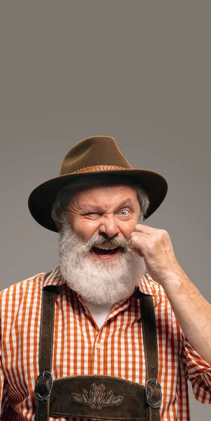 Happy senior man dressed in traditional Austrian or Bavarian costume gesturing isolated on grey studio background — Stock Photo, Image