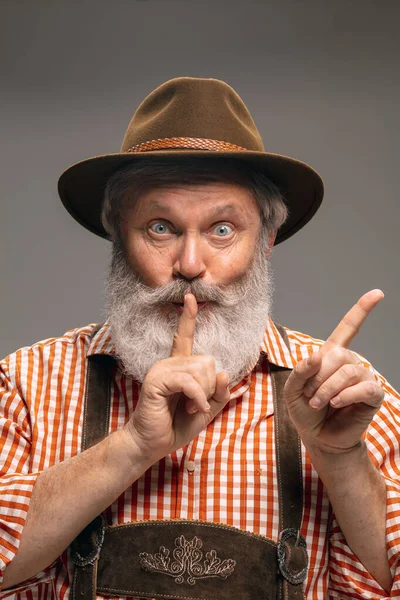 Ευτυχισμένος ηλικιωμένος άνδρας ντυμένος με την παραδοσιακή αυστριακή ή βαυαρική στολή gesturing απομονωμένος σε γκρι φόντο στούντιο — Φωτογραφία Αρχείου