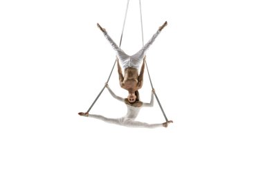 Couple of young acrobats, circus athletes isolated on white studio background. Training perfect balanced in flight