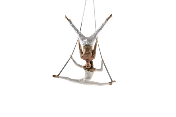 Couple of young acrobats, circus athletes isolated on white studio background. Training perfect balanced in flight — Photo