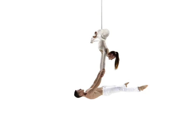 Couple of young acrobats, circus athletes isolated on white studio background. Training perfect balanced in flight — Stockfoto