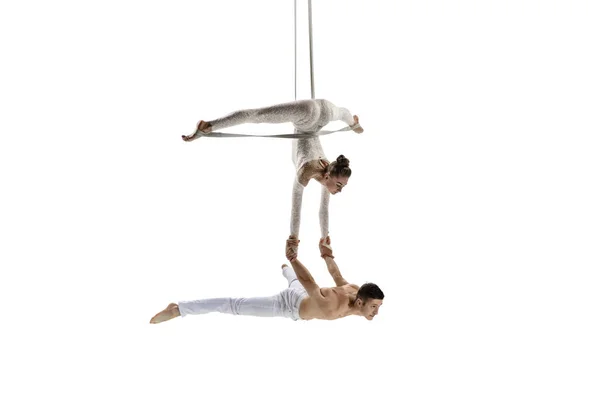 Couple of young acrobats, circus athletes isolated on white studio background. Training perfect balanced in flight — Stock Photo, Image