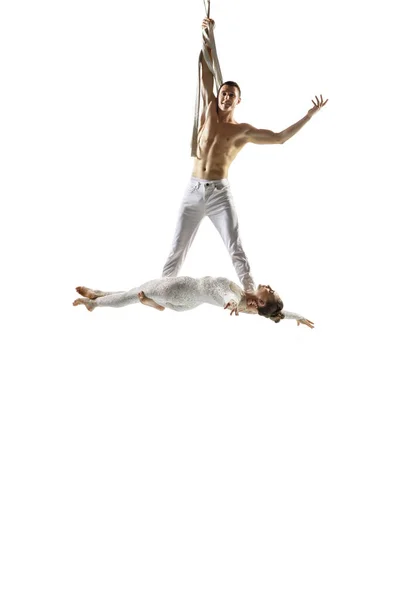 Couple of young acrobats, circus athletes isolated on white studio background. Training perfect balanced in flight — Photo