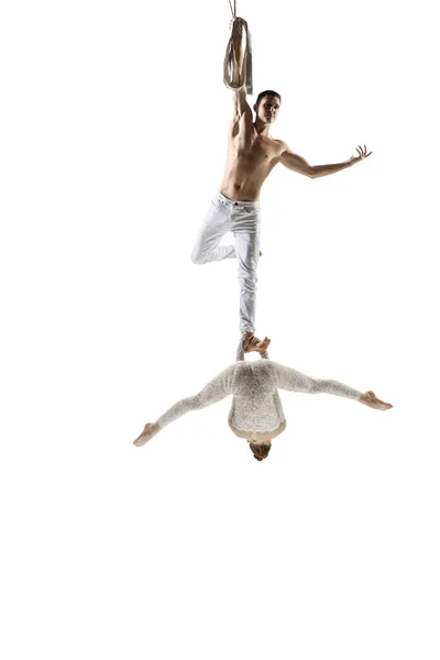 Couple of young acrobats, circus athletes isolated on white studio background. Training perfect balanced in flight — Photo