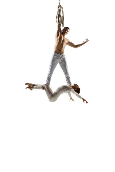 Couple of young acrobats, circus athletes isolated on white studio background. Training perfect balanced in flight — Photo