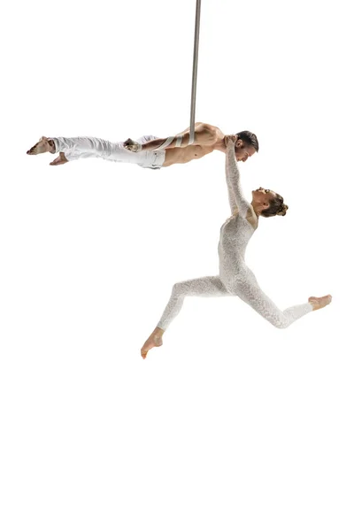 Couple of young acrobats, circus athletes isolated on white studio background. Training perfect balanced in flight — Stockfoto