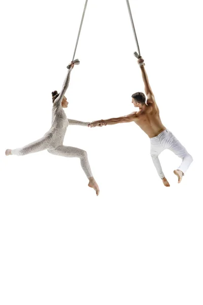 Couple of young acrobats, circus athletes isolated on white studio background. Training perfect balanced in flight — Stockfoto