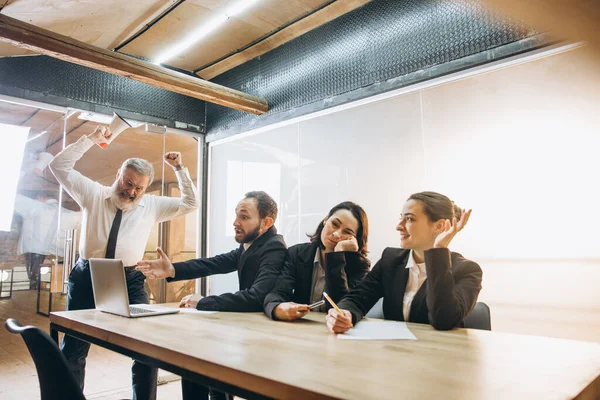 Patron en colère avec mégaphone criant sur les employés au bureau, collègues effrayés et agacés écoutant à la table — Photo