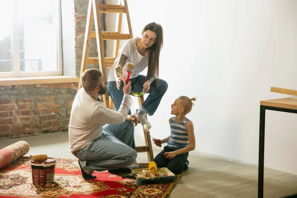 En ung familie som reparerer leiligheten selv. Mor, far og sønn som gjør hjemmearbeid makeover eller renovering – stockfoto