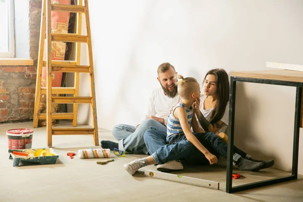 En ung familie som reparerer leiligheten selv. Mor, far og sønn som gjør hjemmearbeid makeover eller renovering – stockfoto