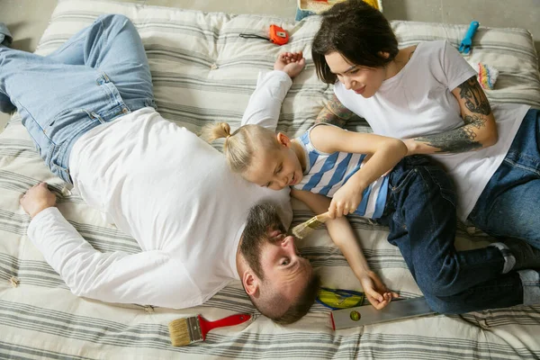 Jonge familie die zelf appartementen repareert. Moeder, vader en zoon doen huisopknapbeurt of renovatie — Stockfoto