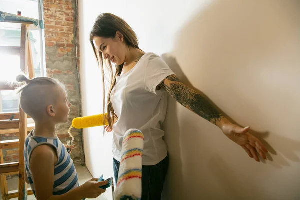 En ung familie som reparerer leiligheten selv. Lykkelig mor og sønn som gjør hjemmearbeid makeover eller renovering – stockfoto