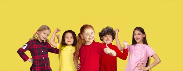 Retrato de niños pequeños haciendo gestos aislados sobre fondo de estudio amarillo con espacio de copia — Foto de Stock
