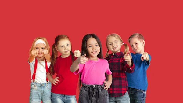 Porträt kleiner Kinder, die isoliert auf rotem Studiohintergrund mit Kopierraum gestikulieren — Stockfoto