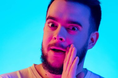 Beyaz adam portresi mavi stüdyo arka planında neon ışıkta izole edilmiş. İnsan duyguları kavramı, yüz ifadesi, satış, reklam.