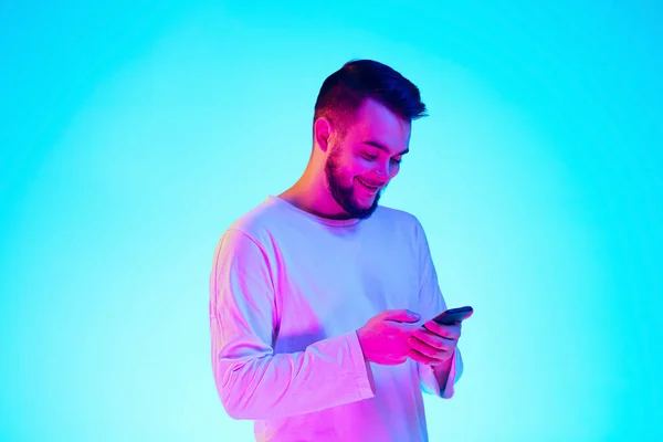 Caucasian mans portrait isolated on blue studio background in neon light. Concept of human emotions, facial expression, sales, ad.