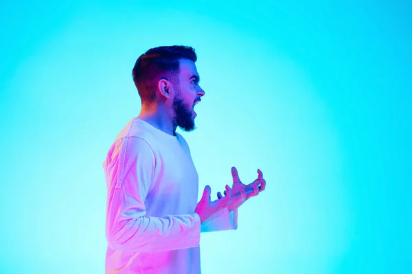 Retrato de hombre caucásico aislado sobre fondo de estudio azul en luz de neón. Concepto de emociones humanas, expresión facial, ventas, anuncios. — Foto de Stock